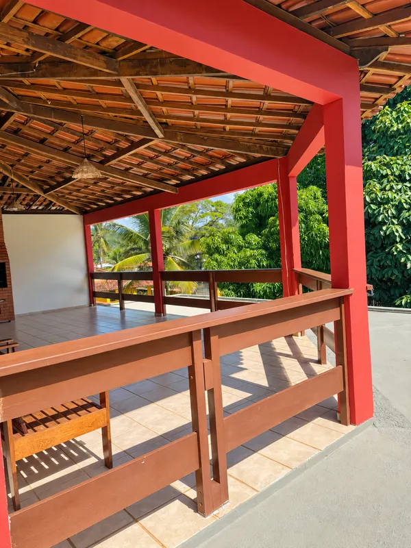 Varanda superior com cobertura de telhas e guarda-corpo de madeira